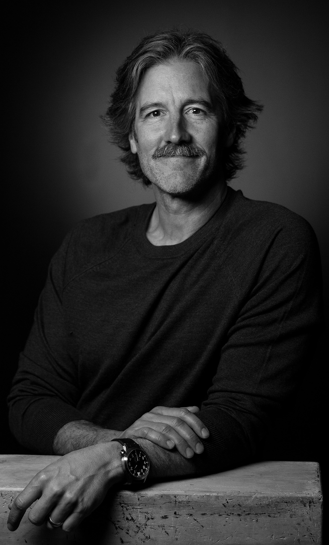 Image of Noah Stokes standing next to a wooden box, in black and white.
